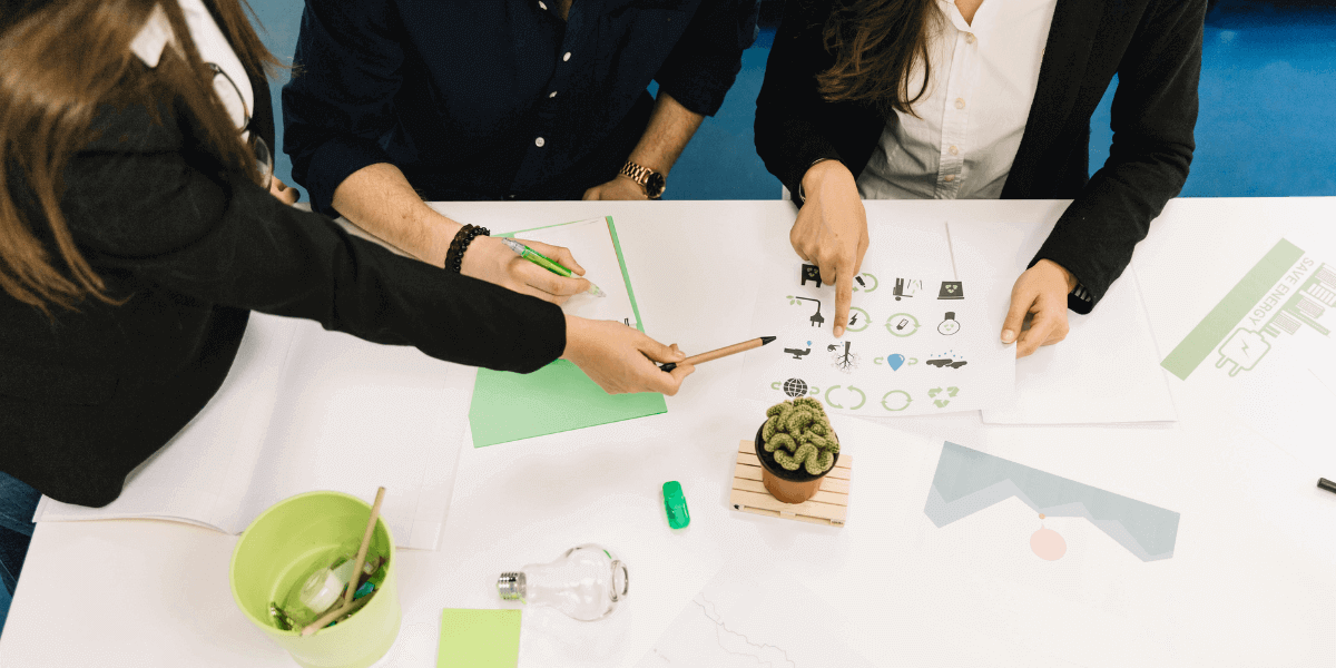 Team members engaged in a discussion, pointing out details with a pen on paper during a collaborative brainstorming session.